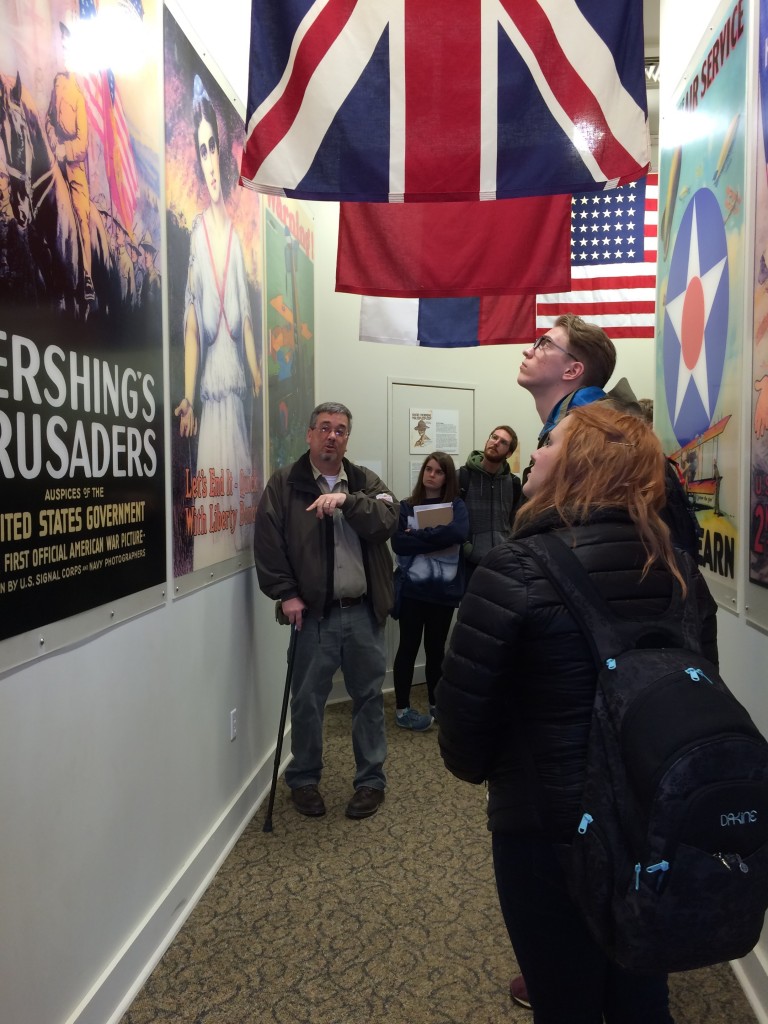Denzil Heaney, Administrator and Curator of the General John J. Pershing Boyhood Home State Historic Site in Lacelede, Missouri, discusses the array of World War I poster images on display in one of the exhibition spaces at the site. Truman students shown are, from left to right, Rachel Pozzo, Anthony LaMarche, Luke Edwards, and Victoria Loos. 