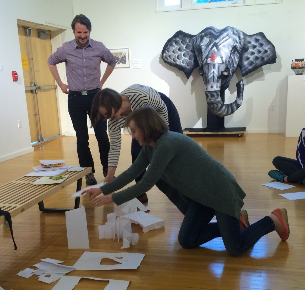 Mike Murawski, Heidi Cook (Gallery Director), and Emma Shouse setting up torn and folded paper responses to a quilt in the University Gallery.