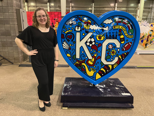Kayla Decker poses next to the heart she painted for the Kansas City Parade of Hearts